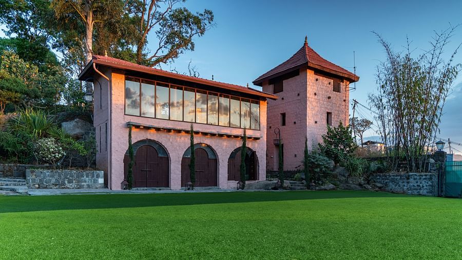 Daytime view of a charming building with a tower, large windows, and a well-maintained lawn. | Mango Hill, Yercaud
