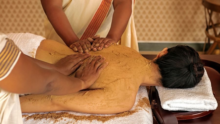 A close-up of a person receiving a massage on their back, with brown substance applied - Shreyas Retreat