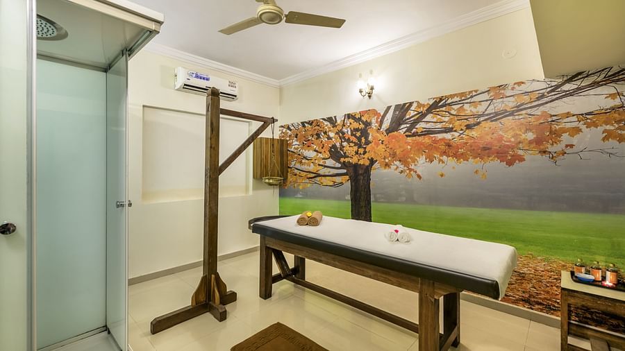 Treatment room of Golden Tulip, Candolim, Goa's spa, featuring a wooden therapy table and a scenic wall mural.