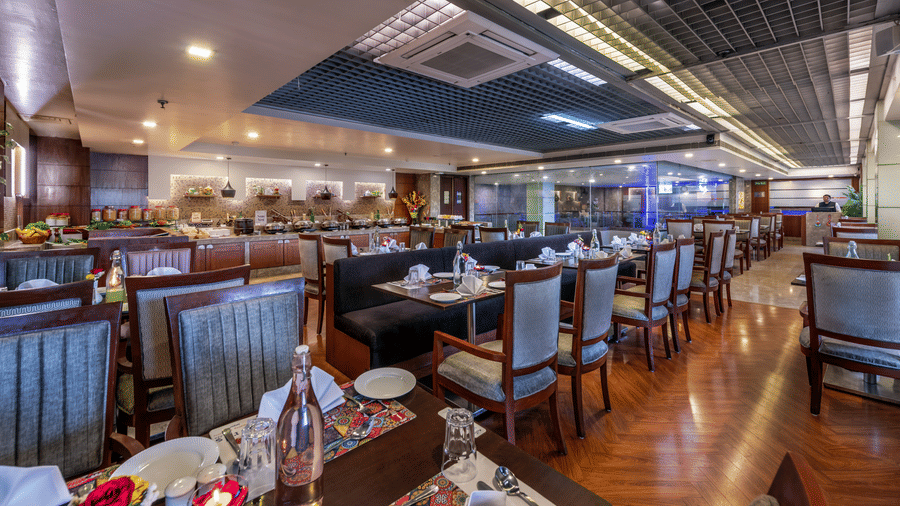 Wide view of a spacious dining area with multiple tables and decorative ceiling at Lords Plaza Jaipur.