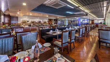 Wide view of a spacious dining area with multiple tables and decorative ceiling at Lords Plaza Jaipur.