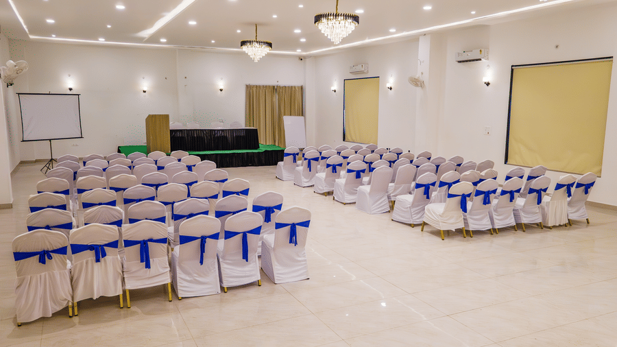 Mystic Jungle Hall seating arrangement at Vedikant Resorts The Mallard Corbett featuring several chairs facing towards the stage which has a podium and a seating arrangement for the panellist. 