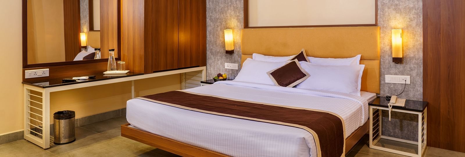 Deluxe room with dressing table and spacious bed at Wyt Hotels, Rameswaram