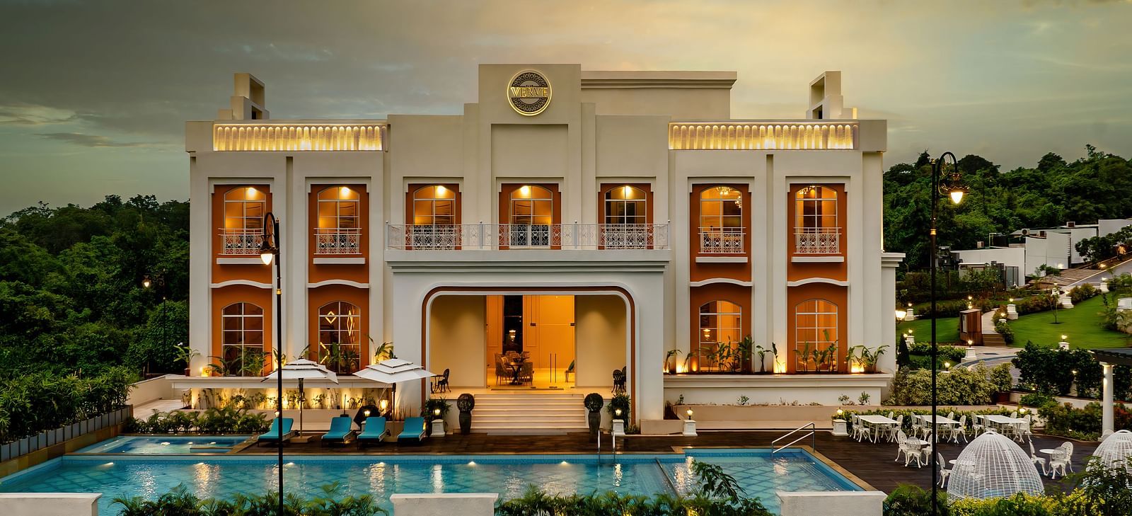Front view shot of the exterior of Imperial Goa with modern architecture along with a swimming pool and a dining area in the foreground.