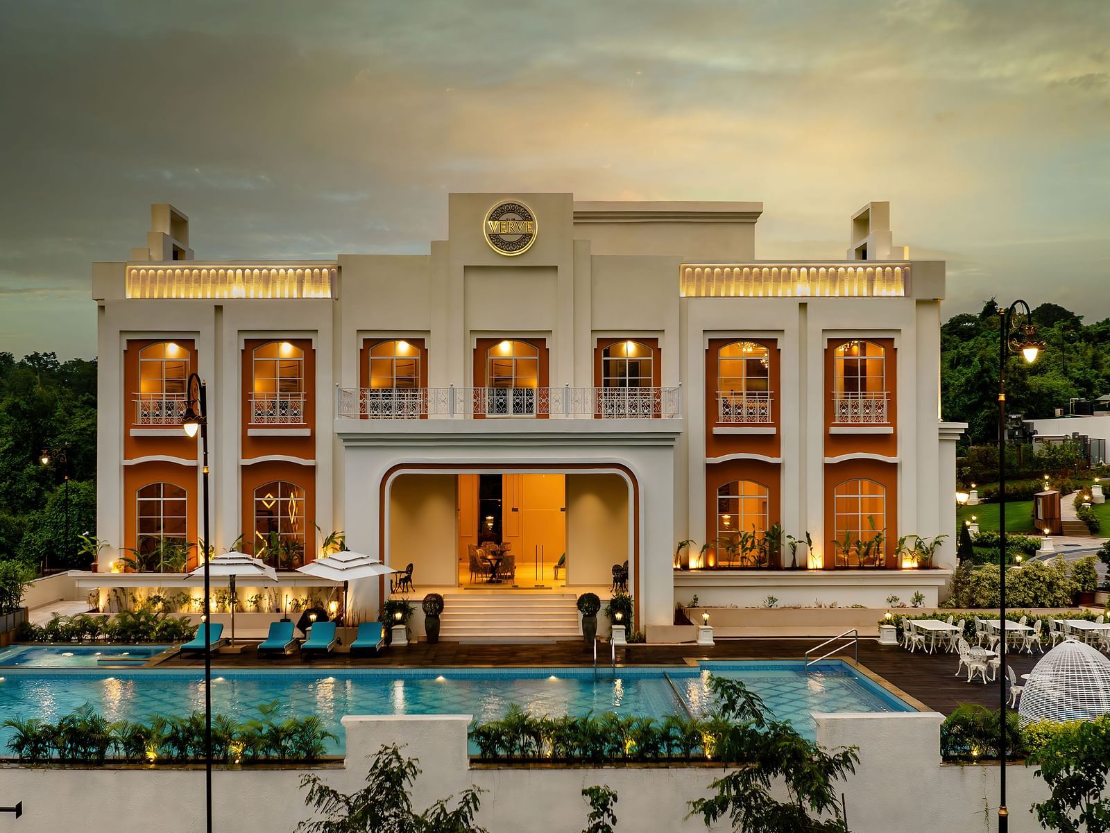 Front view shot of the exterior of Imperial Goa with modern architecture along with a swimming pool and a dining area in the foreground.
