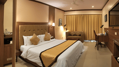 A comfortable hotel room at Uday Samudra Leisure Beach Hotel featuring a king size bed, sofa, work desk under warm lighting