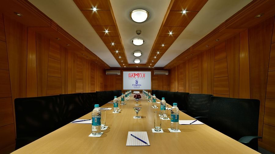 A sleek boardroom with a wooden table, leather chairs, and a screen for presentations. - Tara, Comfort Hotel in Hyderabad - Ramoji Film City.