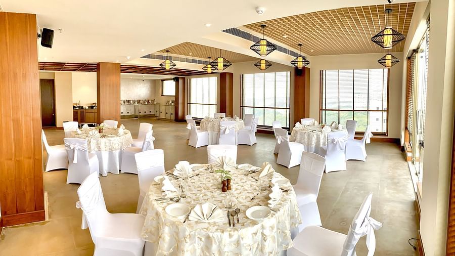 An image of a banquet hall with its seating arrangement and subtle decoration with lighting - Hideaway banquets & Lawns, Greater Noida