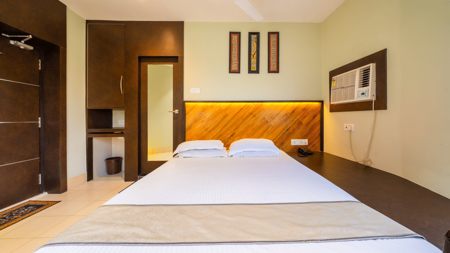 Spacious room featuring a double bed, warm lighting, long mirror, and elegant wall art – Hotel Dolphin Puri