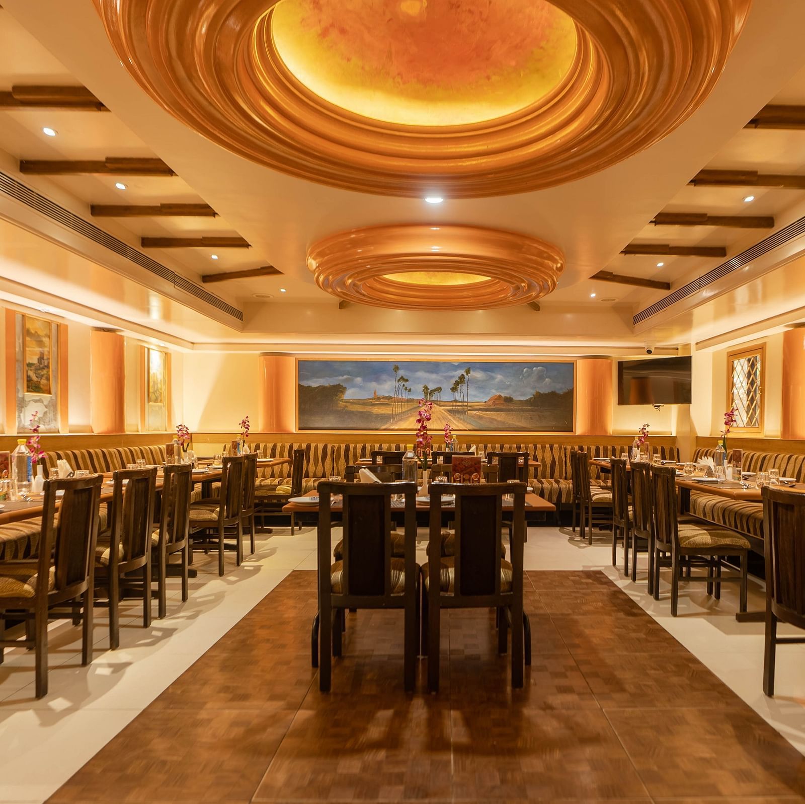 Panoramic view of the Royal Corner restaurant at Hotel Pai Viceroy Jayanagar featuring dining tables, chairs and ambient lighting
