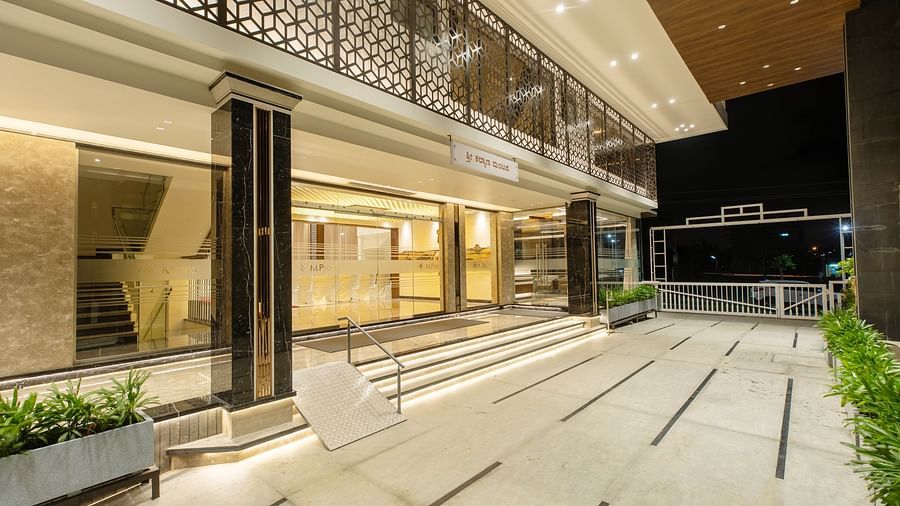 An image showcasing the entrance of M Pro Palace, featuring sleek glass walls and doors.
