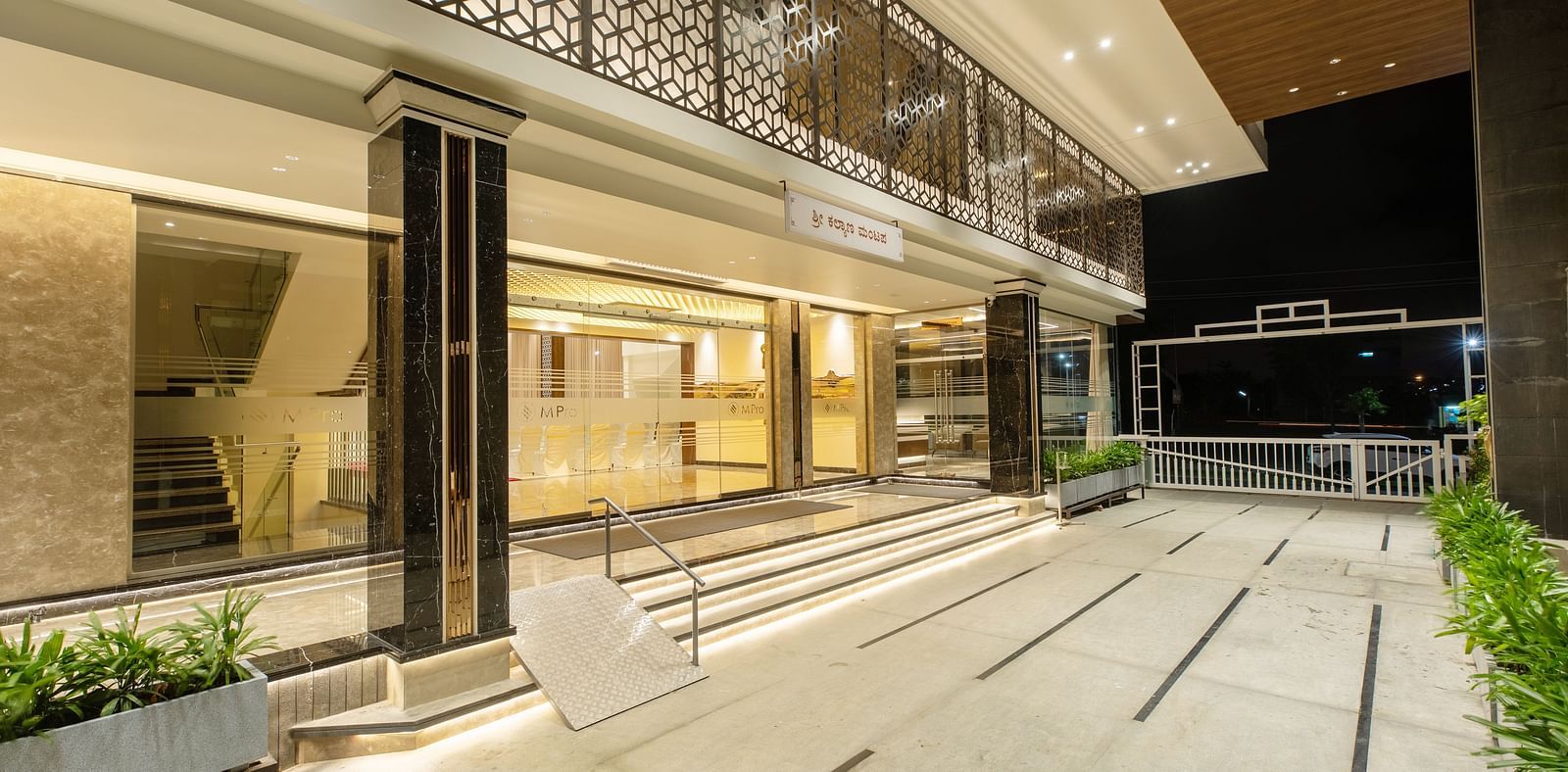 An image showcasing the entrance of M Pro Palace, featuring sleek glass walls and doors.