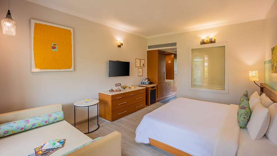room with a king size bed and vibrant yellow interiors at Heritage Village Resorts and spa