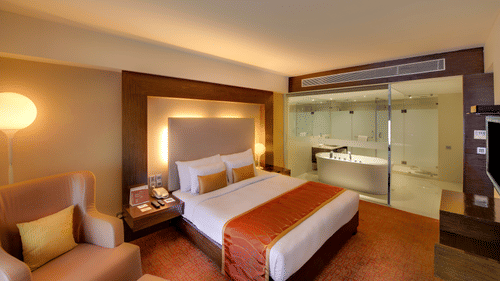 Suite Bedroom with a comfortable bed, sofa with cushions, at Pride Premier Bengaluru.