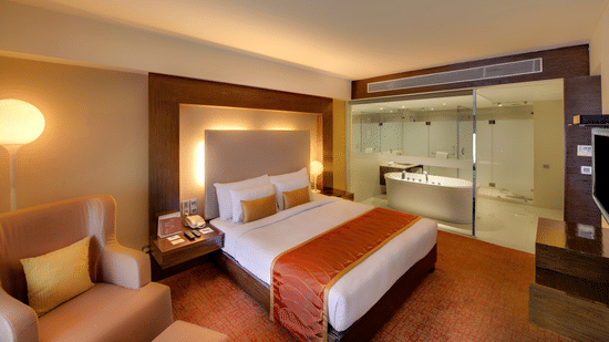 Suite Bedroom with a comfortable bed, sofa with cushions, at Pride Premier Bengaluru.