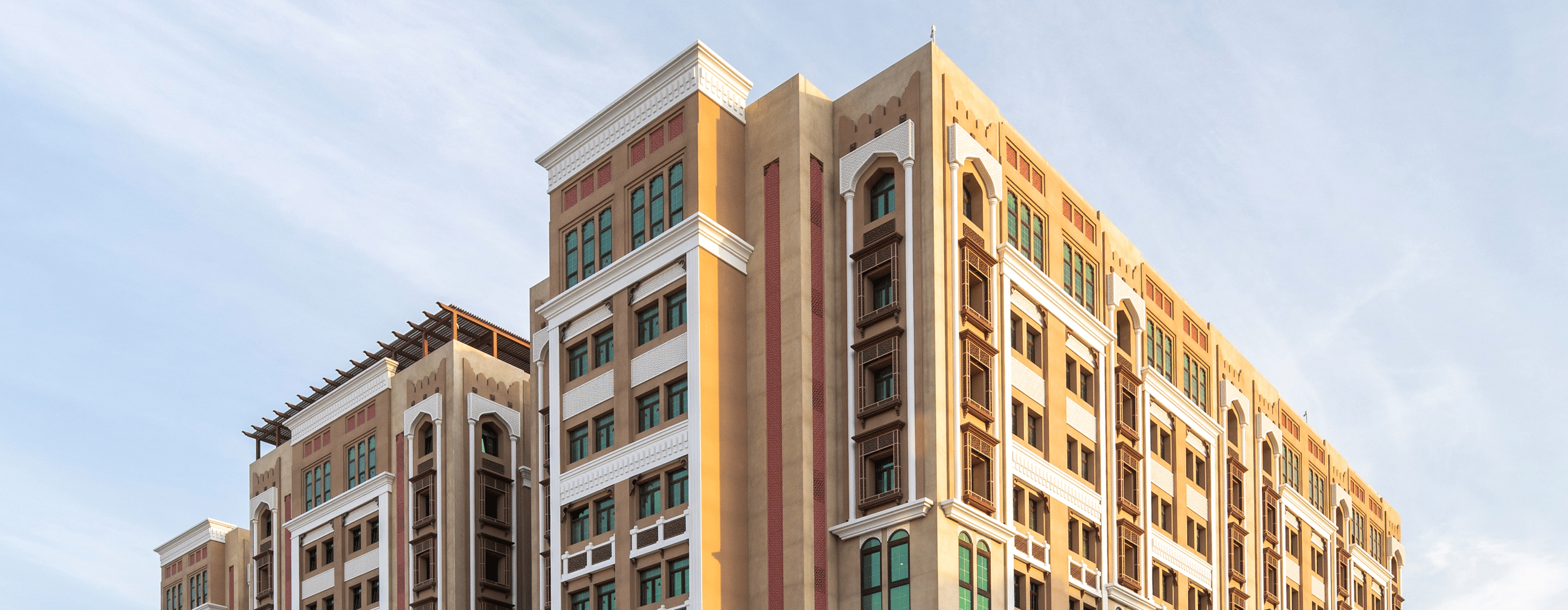 Facade image of La Maison Hotel, Doha with blue sky in the background