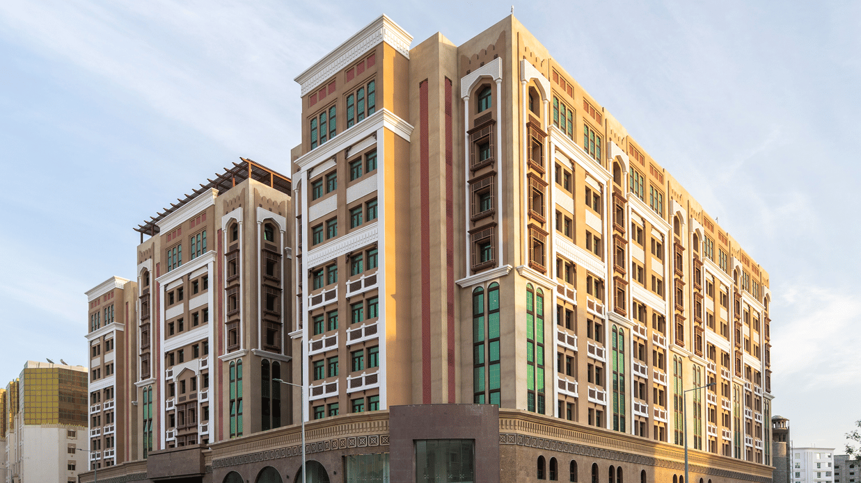 Facade image of La Maison Hotel, Doha with blue sky in the background