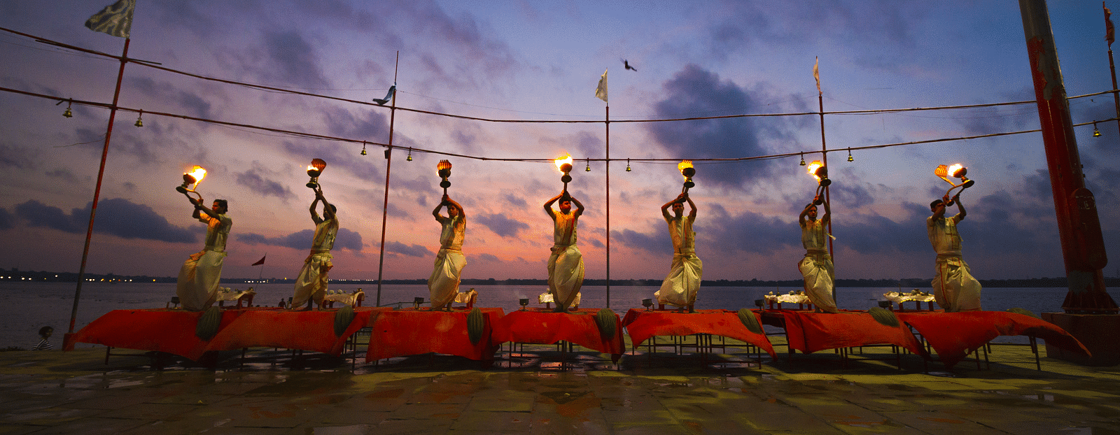 Seven people performing ganga aarti in the evening at the ganga River in Varanasi.