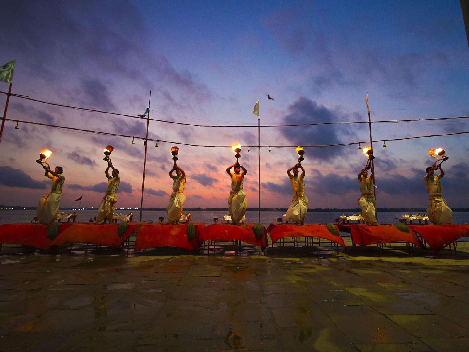 Seven people performing ganga aarti in the evening at the ganga River in Varanasi.