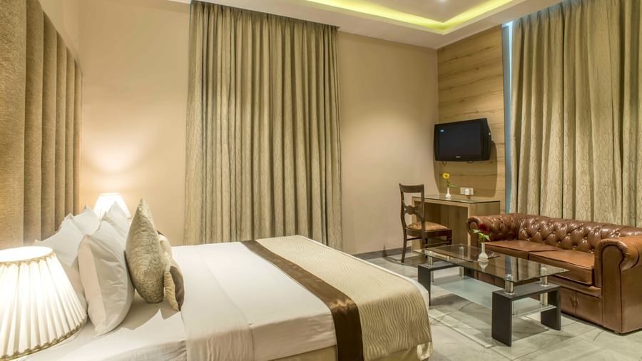 Another view of a cosy hotel room with a single bed and a seating area with a TV | The Citi Residenci Hotel Durgapur