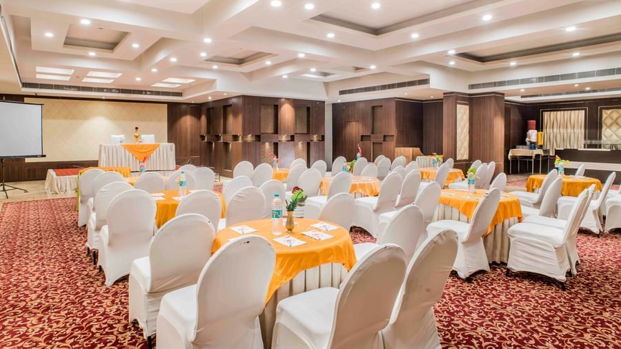 A large banquet hall with numerous round tables and chairs at The Citi Residenci Hotel, Durgapur.