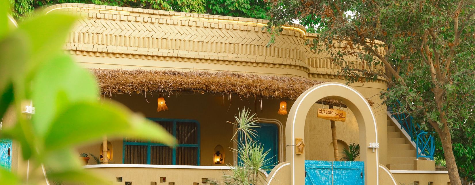 exterior view of the Classic Villas at semi arched gate with blue door at Themis Mudhouse - A Nature's Retreat Resort & Wellness