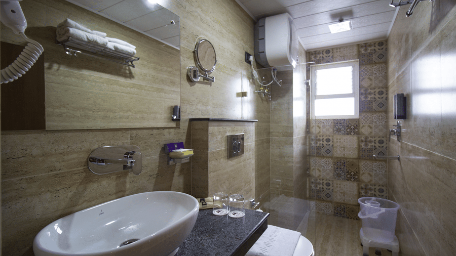 Bathroom with a washbasin, mirror, and shower area at Valmere Lungta Boutique Hotel & Spa, Darjeeling.