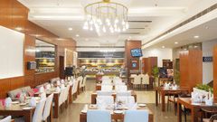 A wide angle view of the  restaurant interior at Nemesia featuring chandeliers, wooden furniture, tables arranged with napkins, water glasses, and plates
