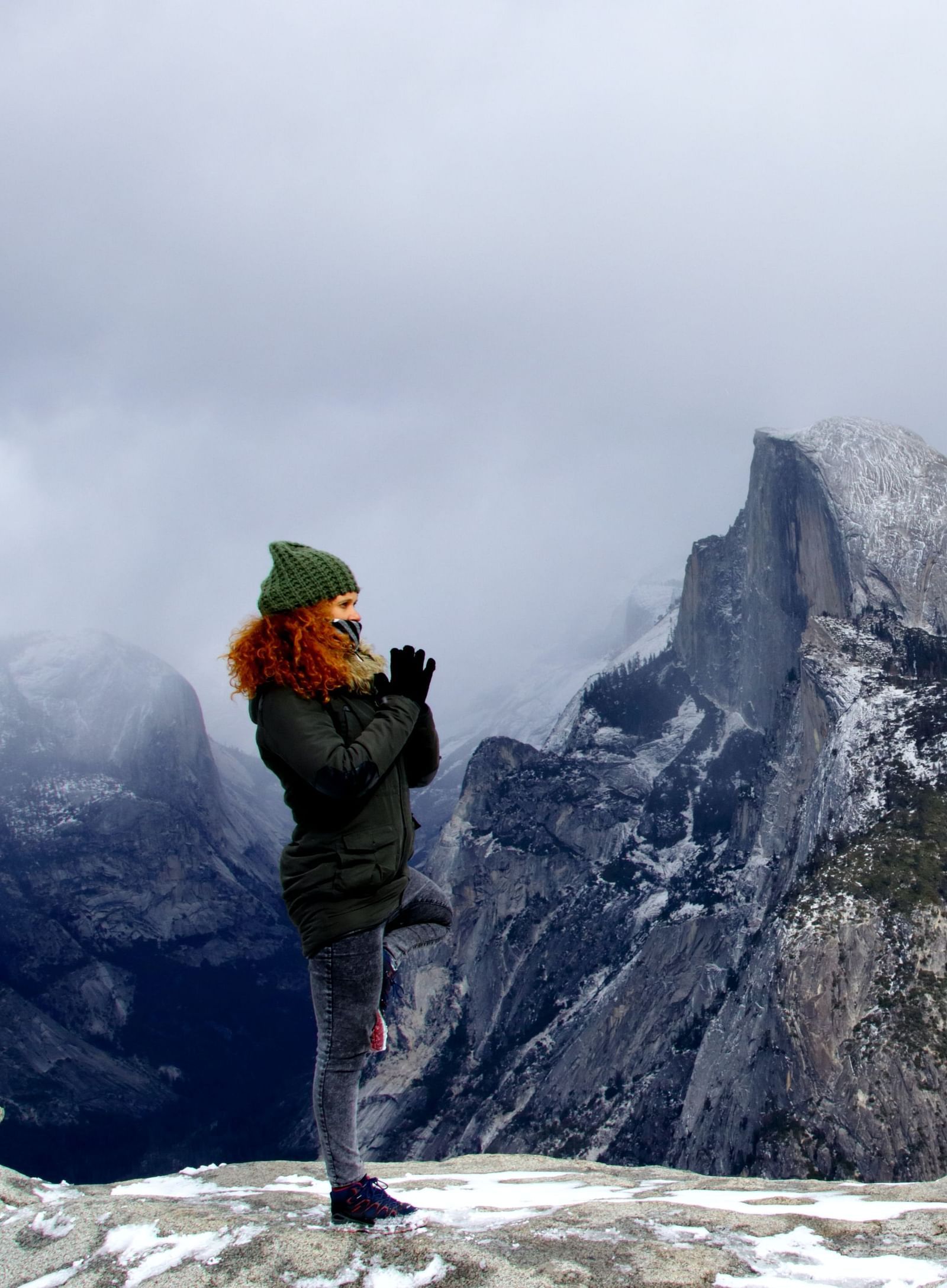 a woman performing a yoga asana on top of a mountain with snow on it and another mountain in the background