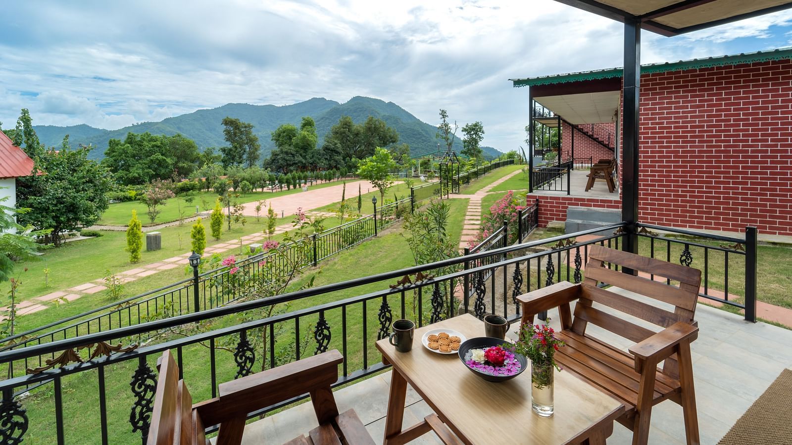 the back view of the room with a balcony having chairs and tables under a canopy inside one of the rooms - Neer Ganga Resorts
