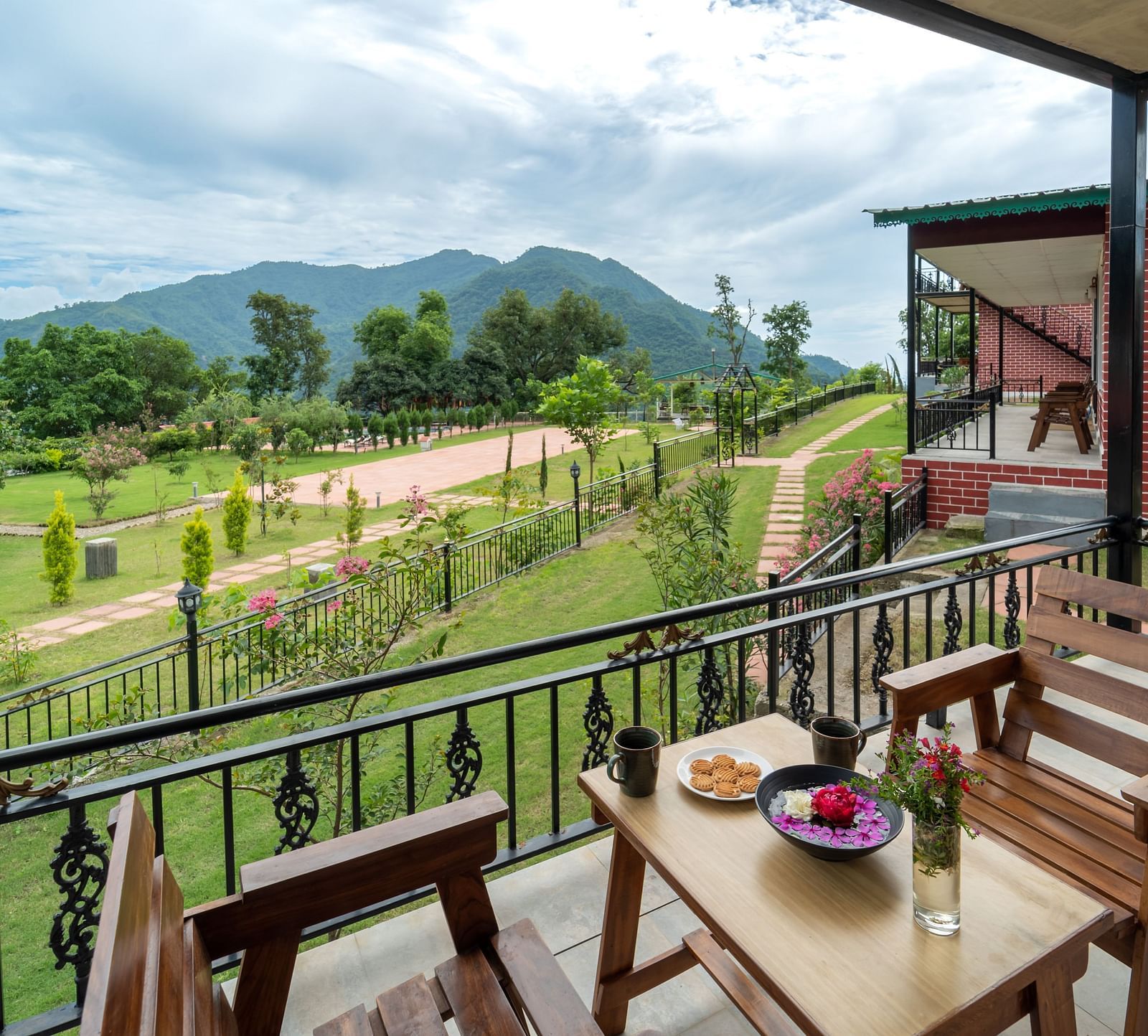 the back view of the room with a balcony having chairs and tables under a canopy inside one of the rooms - Neer Ganga Resorts