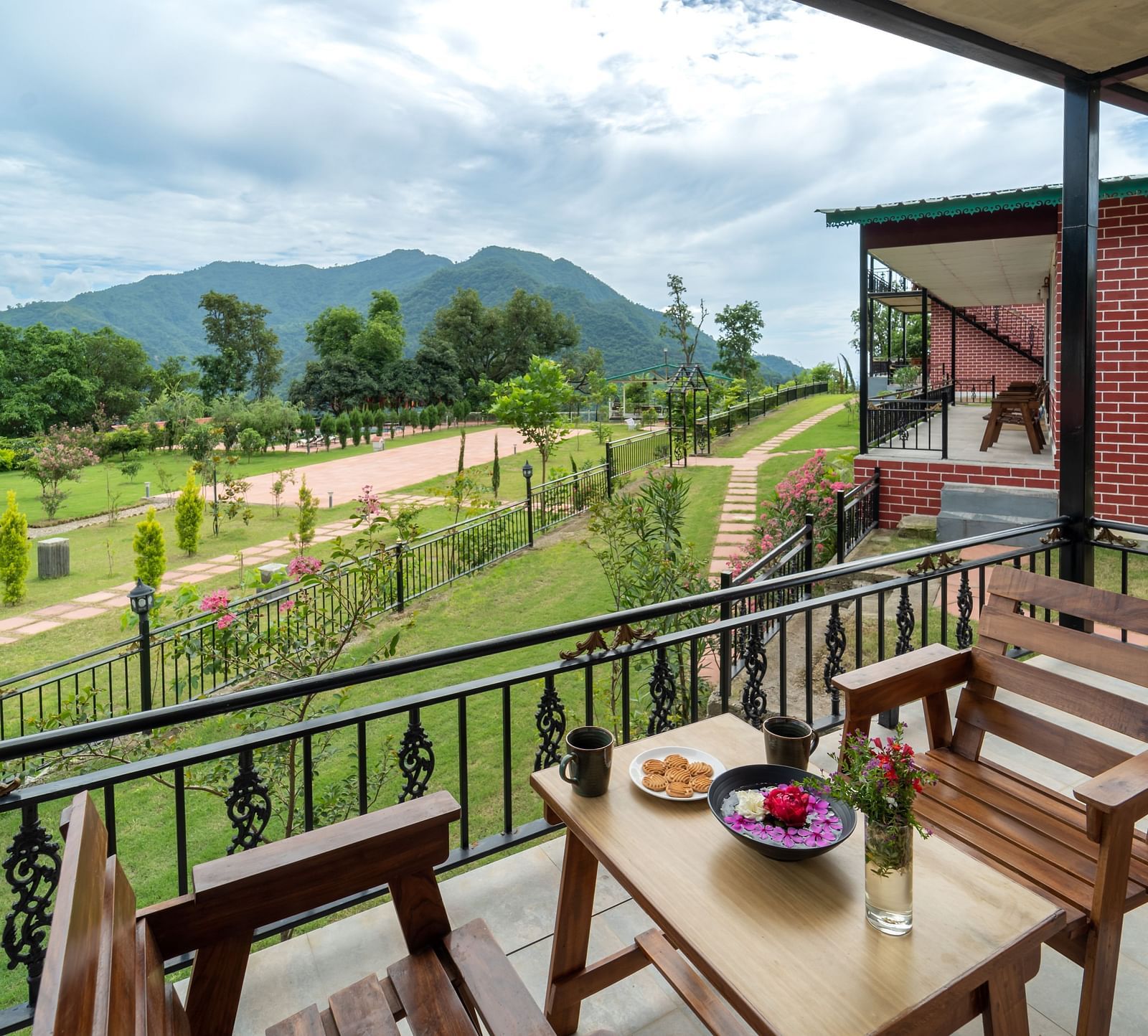 the back view of the room with a balcony having chairs and tables under a canopy inside one of the rooms - Neer Ganga Resorts