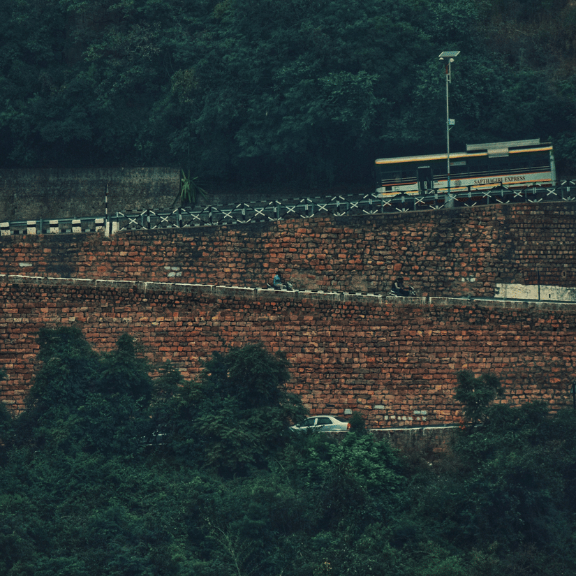 Vehicles moving along winding ghat roads carved into densely forested hills during misty weather in the Tirupati region.