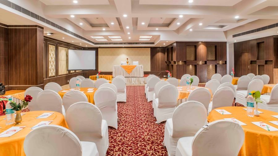 A large banquet hall with round tables and chairs ready for a function at The Citi Residenci Hotel, Durgapur.