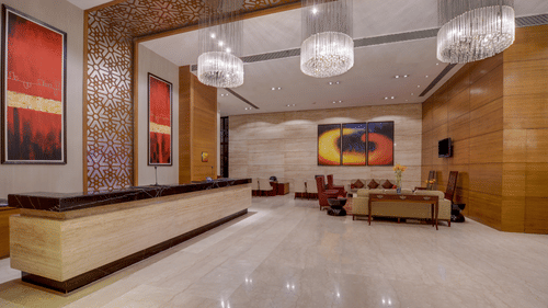 Image of the reception at Pride Plaza Hotel in Kolkata with a lobby area beside the reception desk