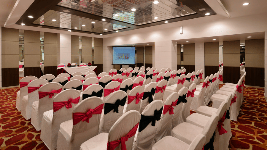 Theatre style seating arrangement with well-lit ambience and a projector screen upfront