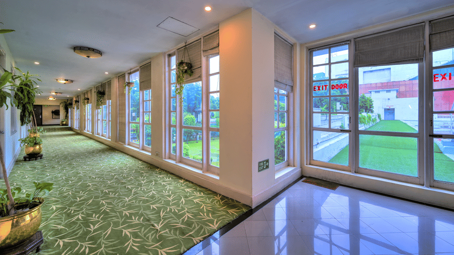 A lounge at The Clarks Varanasi, with pillars, carpets and windows.