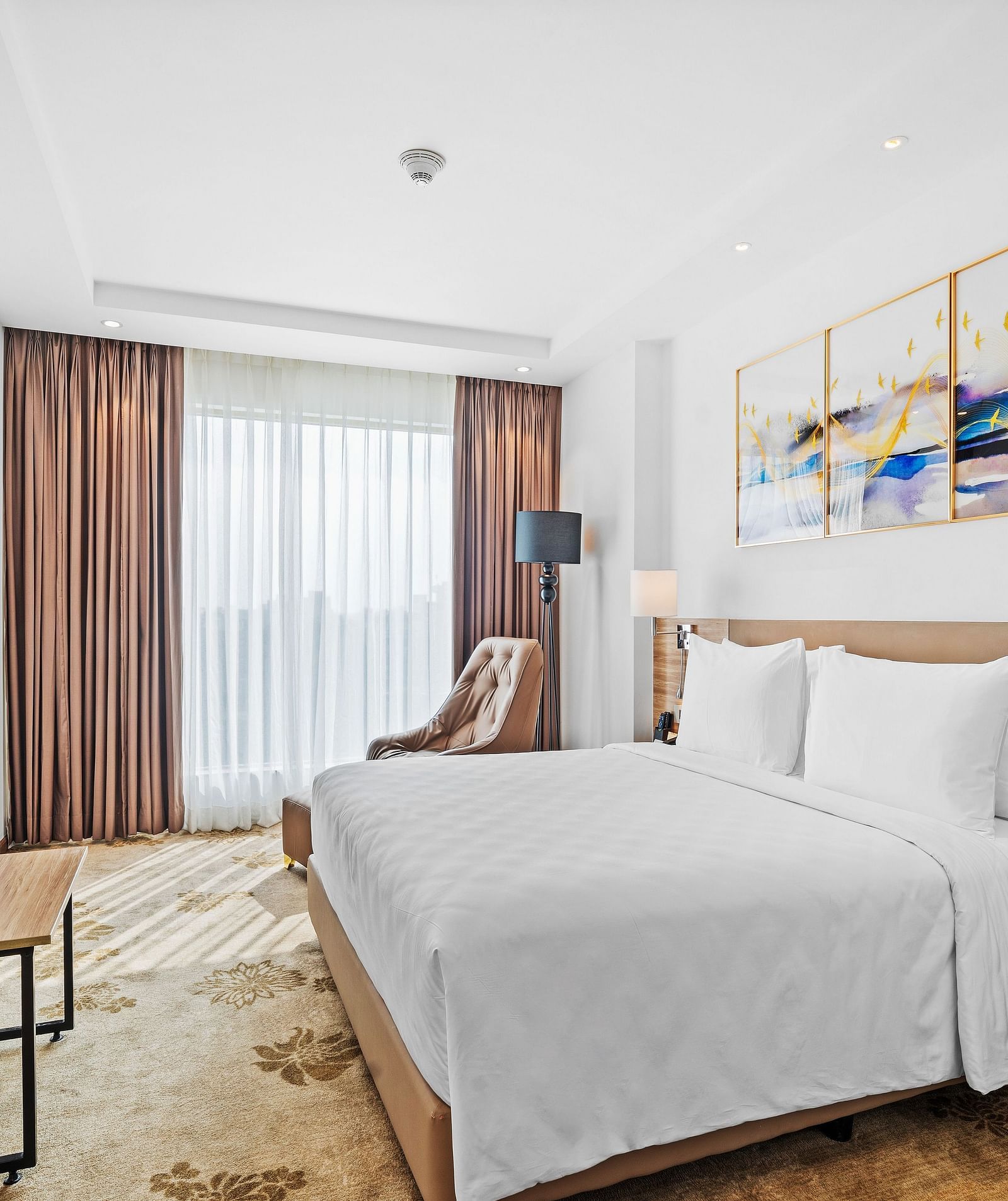 An image of a king size bed in front of a TV of a Deluxe Room at Grand Vijayawada by GRT Hotels.