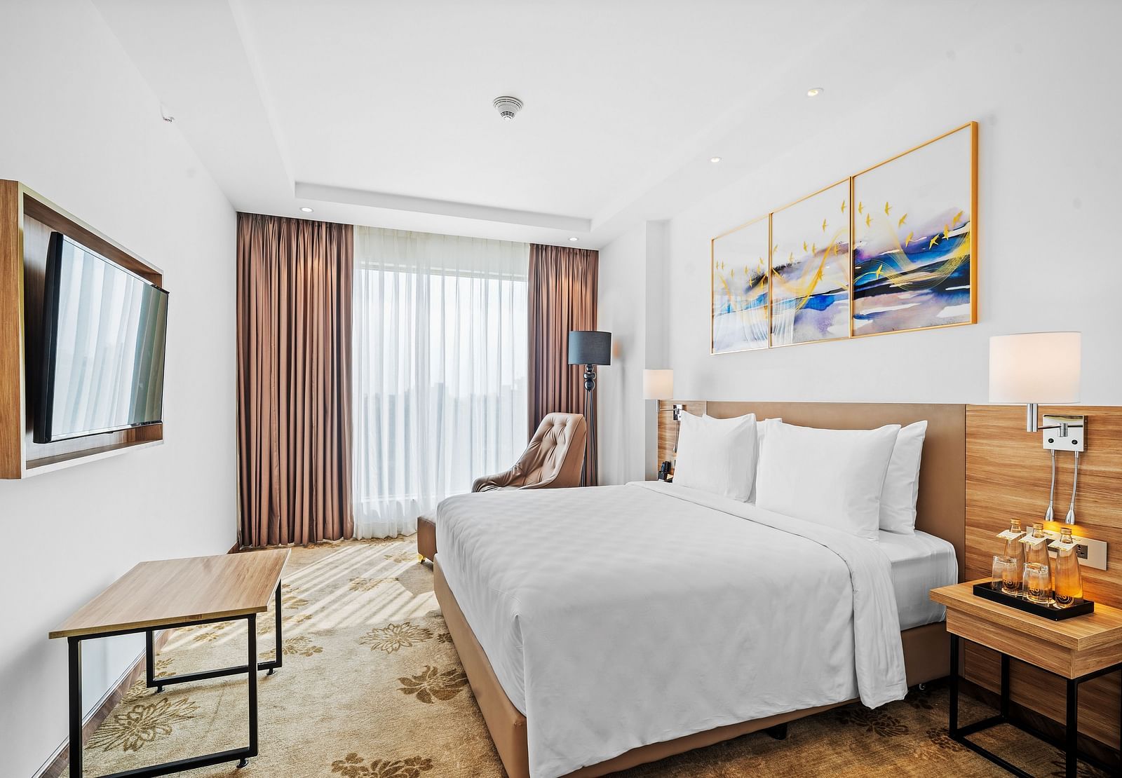 An image of a king size bed in front of a TV of a Deluxe Room at Grand Vijayawada by GRT Hotels.