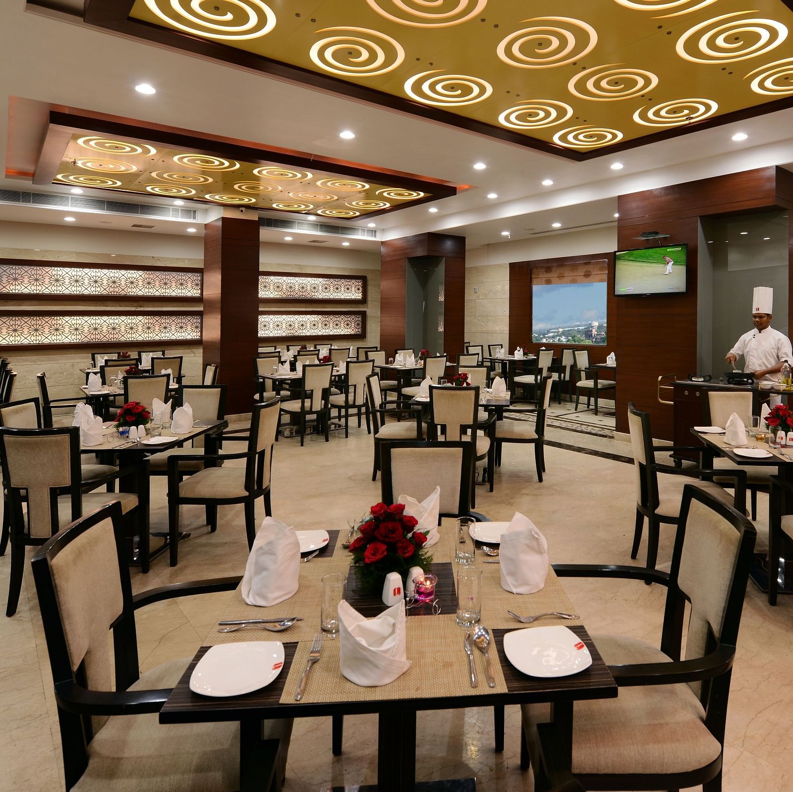 A restaurant seating area with neatly arranged chairs and tables, well-lit ambience and glass windows overlooking greenery