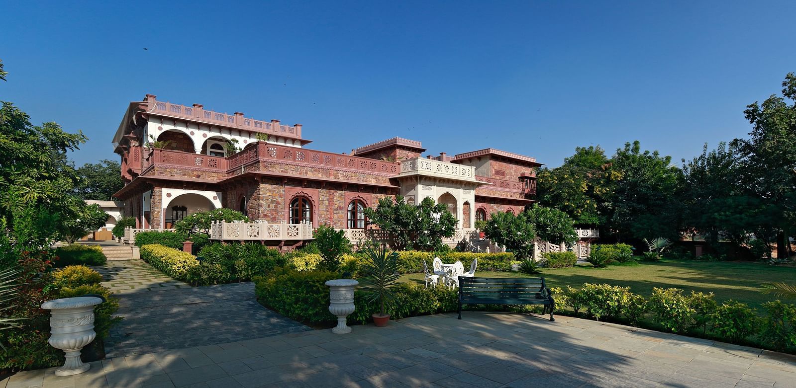 A grand Indian villa surrounded by lush gardens under a clear blue sky - Khas Bagh, Jaipur.