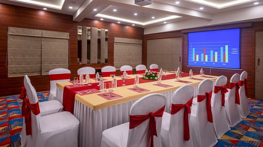 Conference room set up with banquet seating and projector screen, ideal for meetings and events - Lords Eco Inn Shapar Rajkot