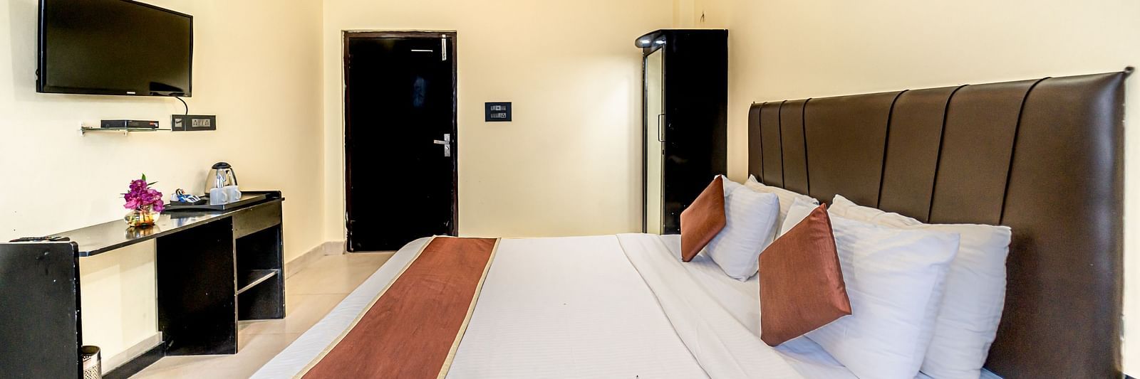 a bedroom at Flutter Hotels & Resorts featuring a bed, a television and a wardrobe