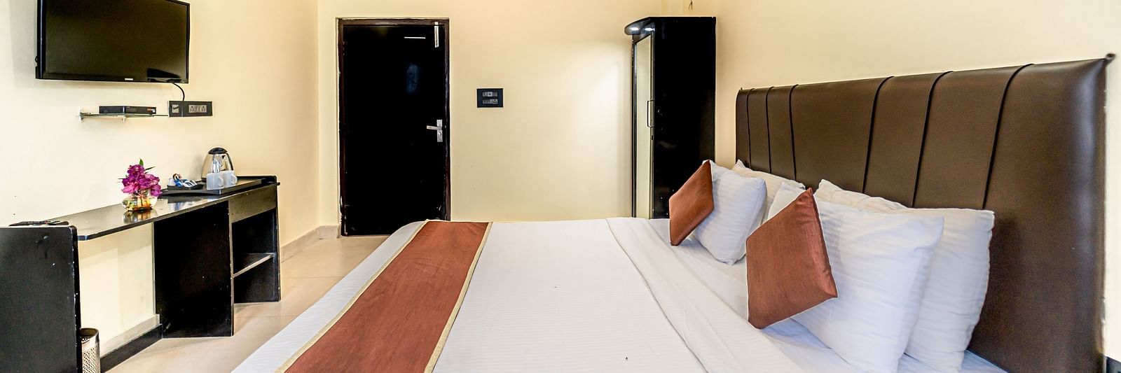 a bedroom at Flutter Hotels & Resorts featuring a bed, a television and a wardrobe