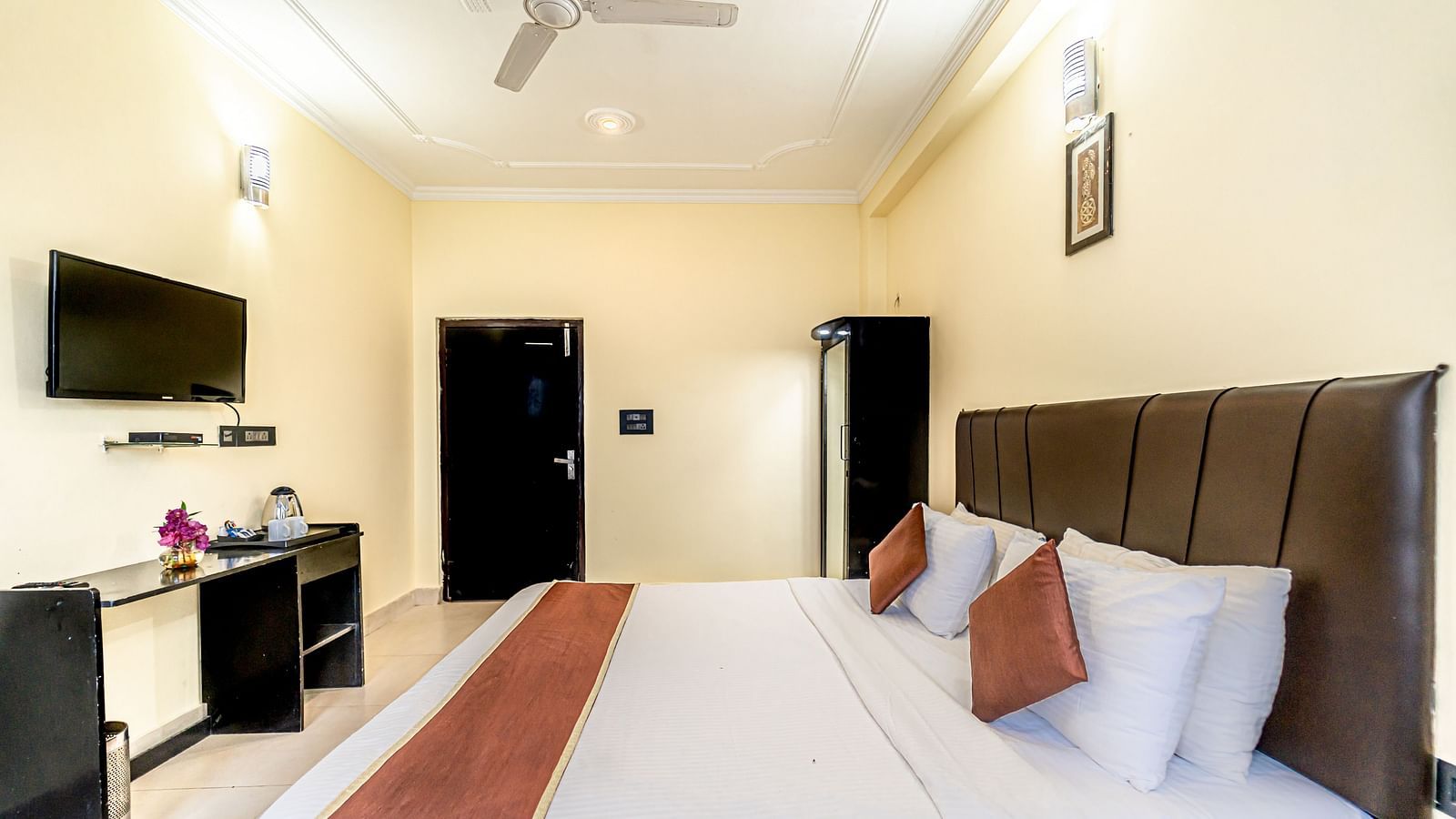 a bedroom at Flutter Hotels & Resorts featuring a bed, a television and a wardrobe