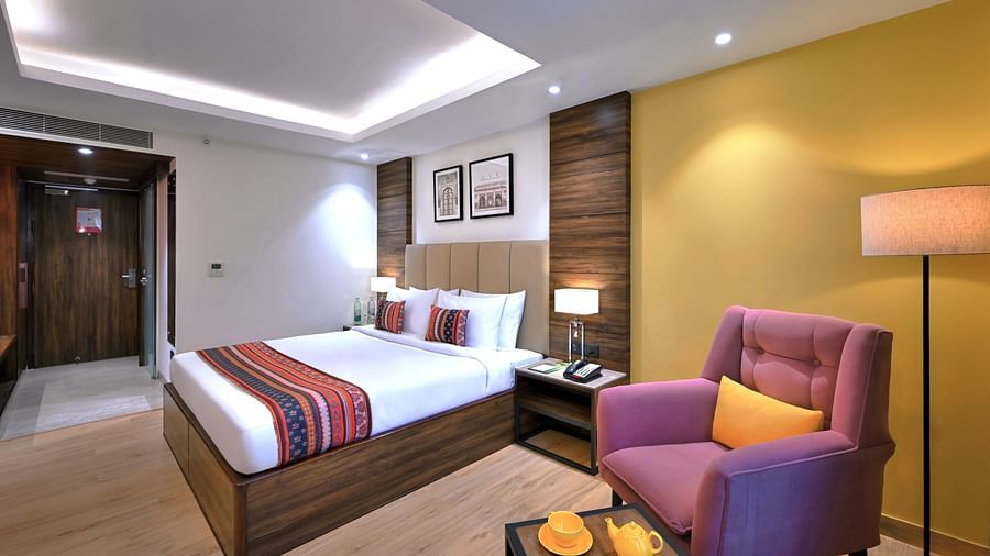 An image of a bed in our Deluxe Room with a comfortable couch to sit and relax on the side - Golden Tulip, Agra