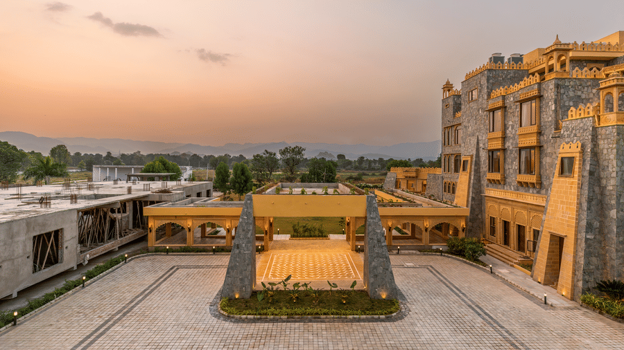 A wide-angle view of the internal courtyard and stone facade at EsthereaRaj Leela, Ranakpur, during sunset.