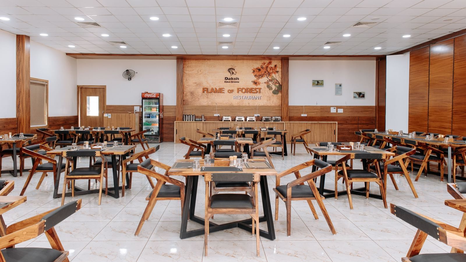A wide angle shot of the restaurant with various seating arrangements and overhead lighting -Daksh Eden Greenz, Sasan Gir