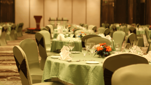 A hall with chairs and tables arranged for an event at Pride Plaza, New Delhi.