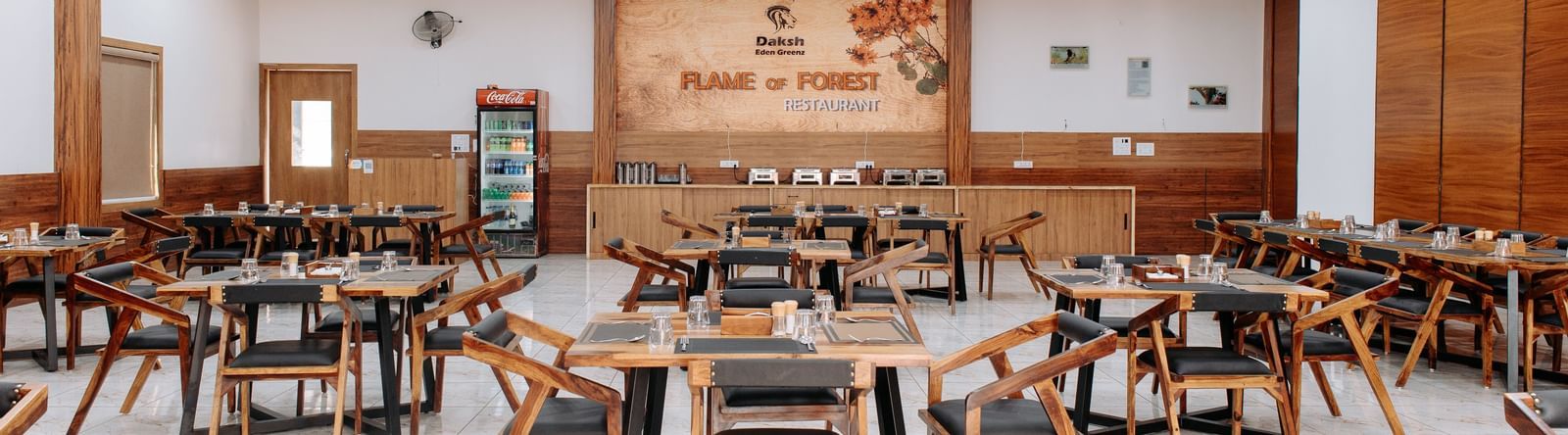 A wide angle shot of the restaurant with various seating arrangements and overhead lighting -Daksh Eden Greenz, Sasan Gir